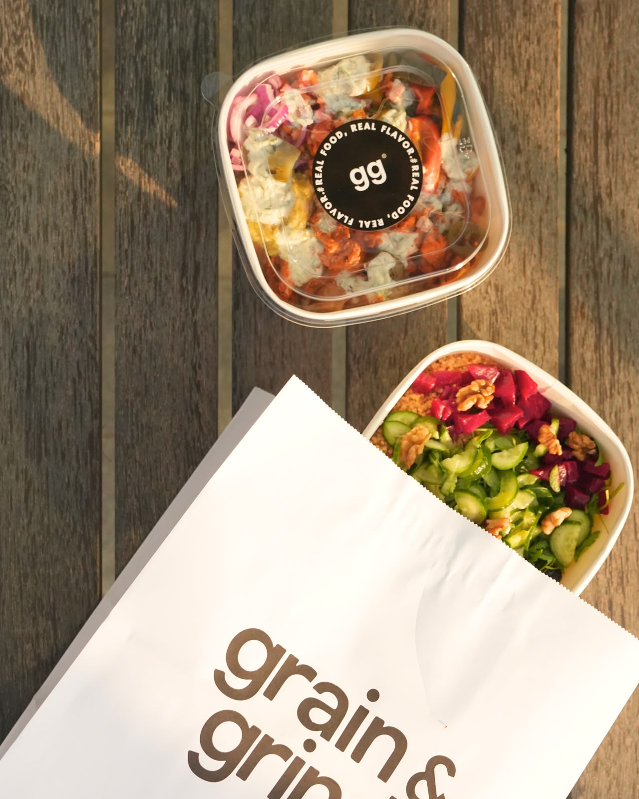 Grain & Grind salad bowls and takeaway bag on a wooden table